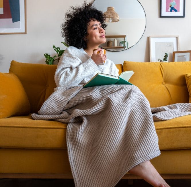 mujer sentada en un sofá con una manta