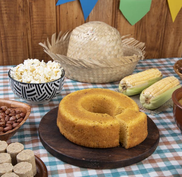 Un sombrero de paja, torta de maíz, maíz y maní están sobre una mesa con un mantel a cuadros.