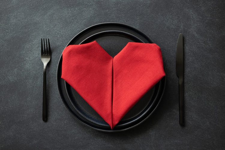 cubiertos negros y plato negro con una servilleta roja en forma de corazón