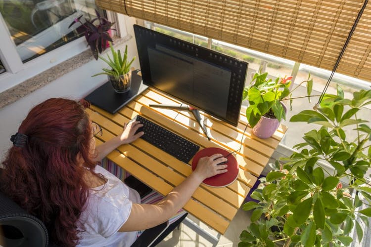 Mujer pelirroja que trabaja en una oficina en casa en el balcón