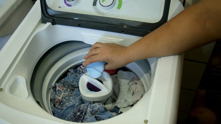 mujer poniendo jabón en la lavadora