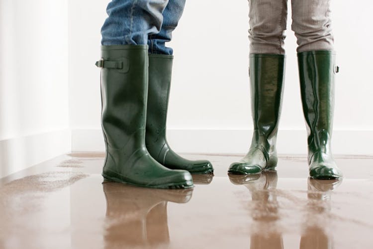 Dos personas usan botas protectoras para pisar un suelo anegado