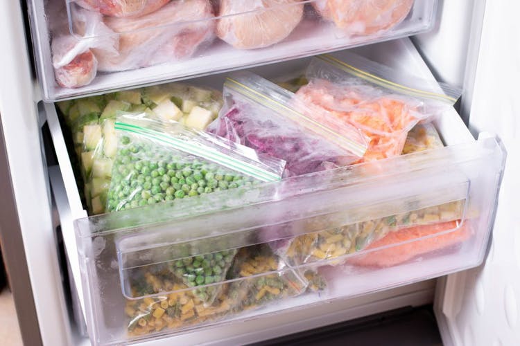 Cajón abierto de un congelador vertical lleno de alimentos