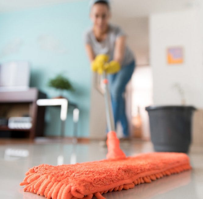 La mujer usa un trapeador para limpiar el piso