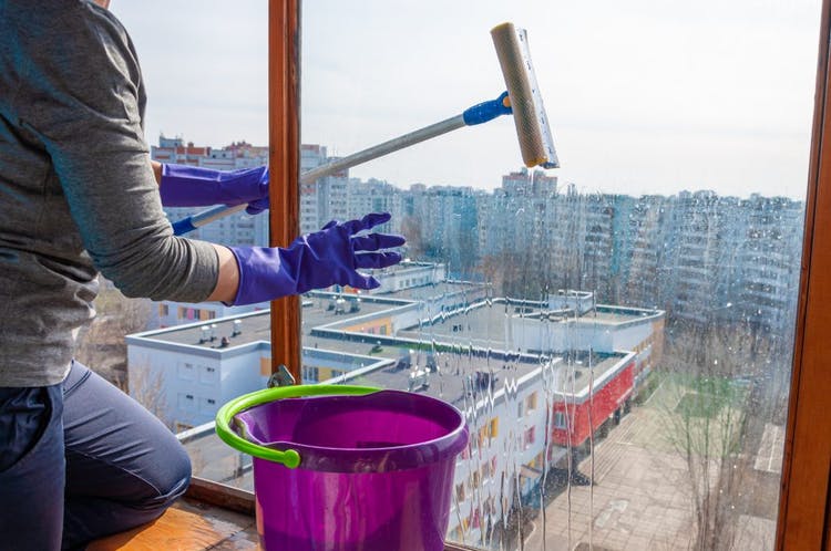 mujer limpiando ventana de cristal