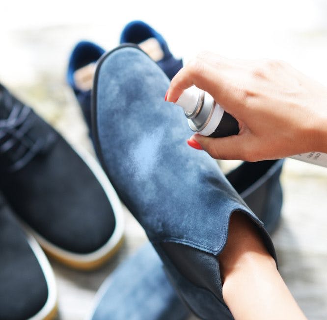 Mujer usa un spray para limpiar una bota de gamuza