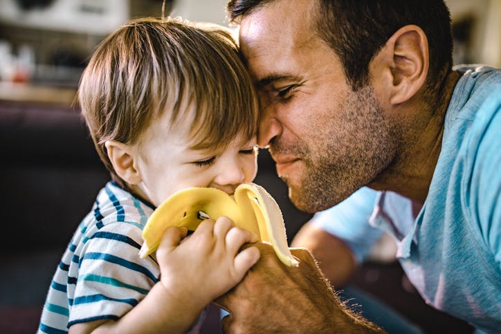 Un padre está alimentando a su hijo con plátanos.