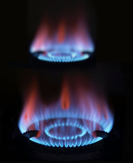 Dos estufas con llamas encendidas.  Ambos son de color azul y se queman puros.  El fondo de la foto es completamente oscuro, solo se ven las llamas azules.