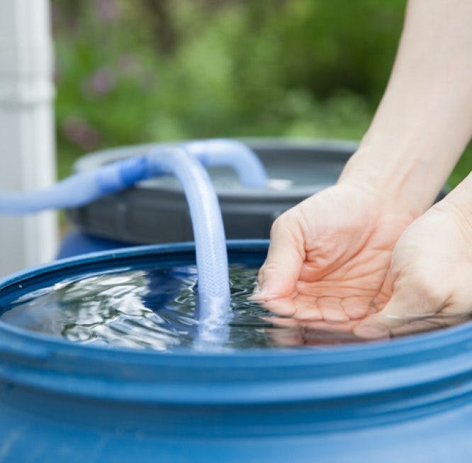 Un hombre está poniendo sus manos sobre una cisterna de agua recogida de la lluvia.