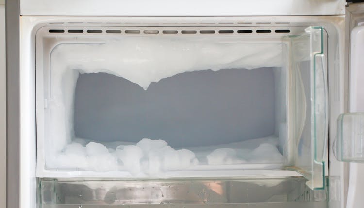 Un congelador con mucho hielo y sin comida.