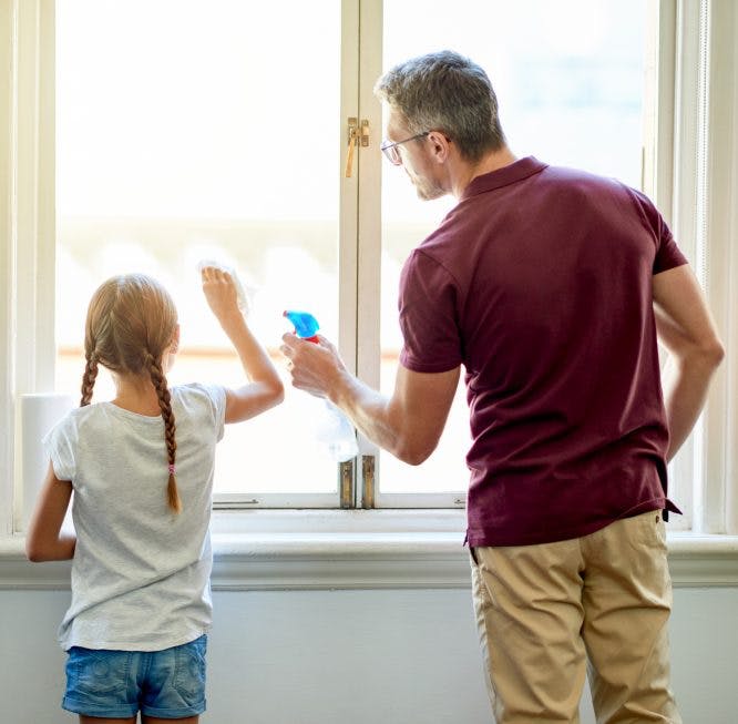 Padre e hija limpiando las ventanas de la casa juntos
