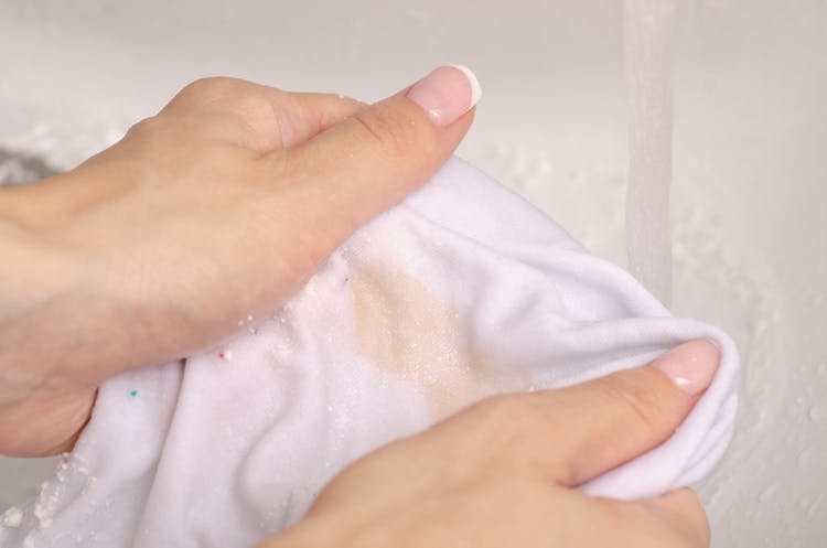 mujer frotando mancha de ropa blanca