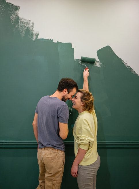 pareja pintando la pared verde