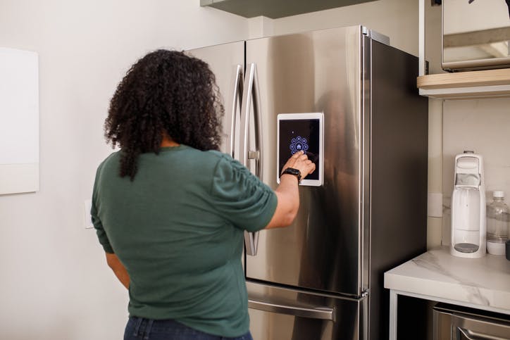mujer usa ipad que se queda en la puerta del refrigerador