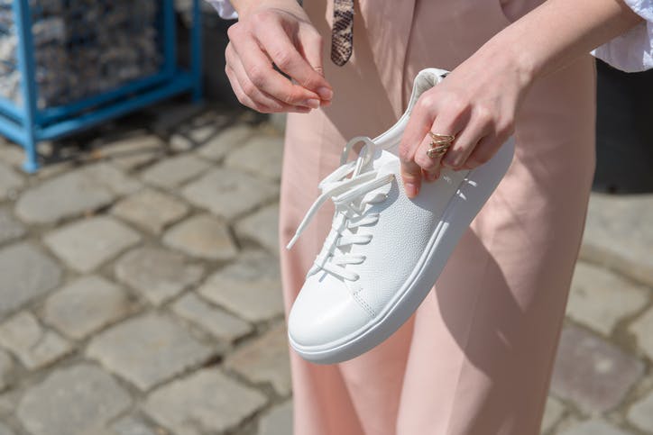 mujer sostiene zapatillas blancas