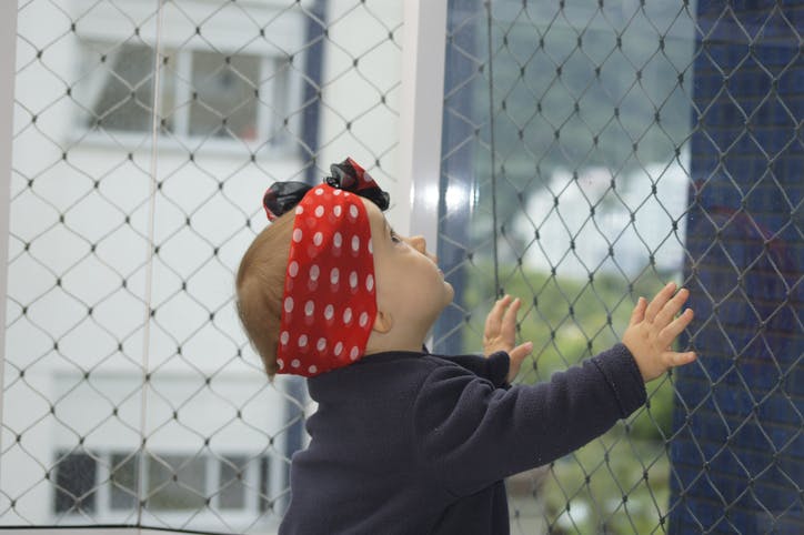 niño pequeño que sostiene la pantalla de protección de la ventana