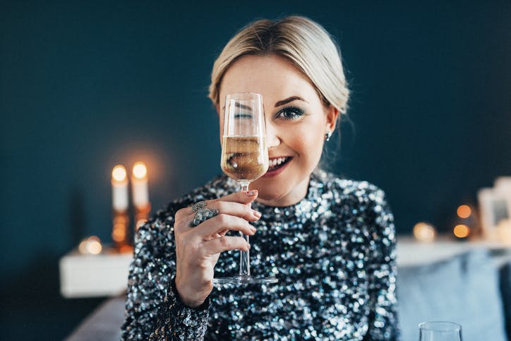 mujer con un vestido de cóctel brillante y sosteniendo una copa de champán