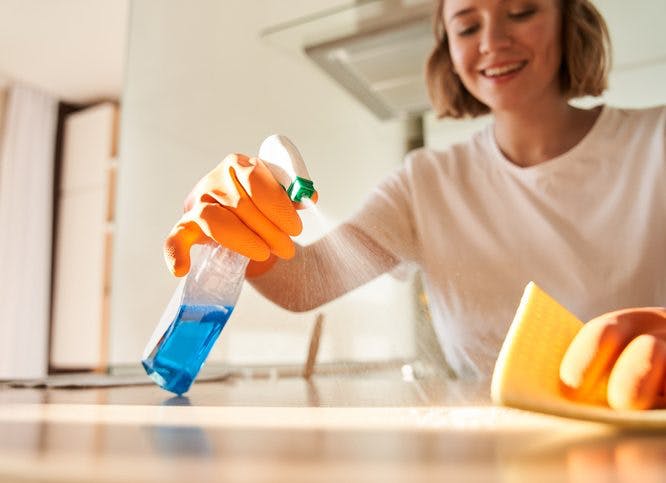 mujer limpia la encimera de la cocina con un limpiador multiusos