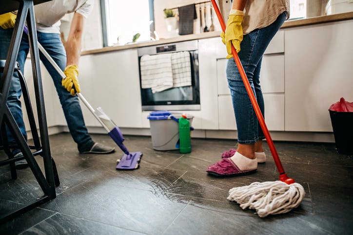 pareja limpia el piso de la cocina